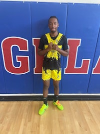 a man in a yellow and black uniform standing in front of a basketball court