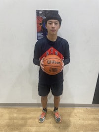 a boy holding a basketball in front of a wall