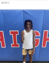 a young man with dreadlocks standing in front of a high school sign