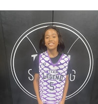 a young girl in a purple jersey standing in front of a sign