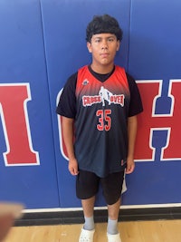 a young boy in a basketball uniform standing in front of a wall