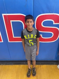 a young boy standing in front of a basketball court