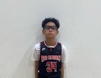 a young boy in a basketball uniform posing for a picture
