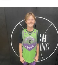 a young boy in a basketball uniform standing in front of a wall