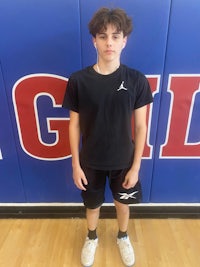 a young boy in a basketball uniform posing for a picture