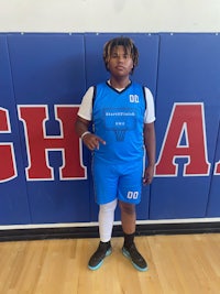 a young boy standing in front of a basketball court