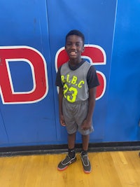 a young boy standing in front of a basketball court