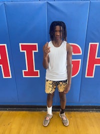 a young man with dreadlocks standing in front of a high school sign